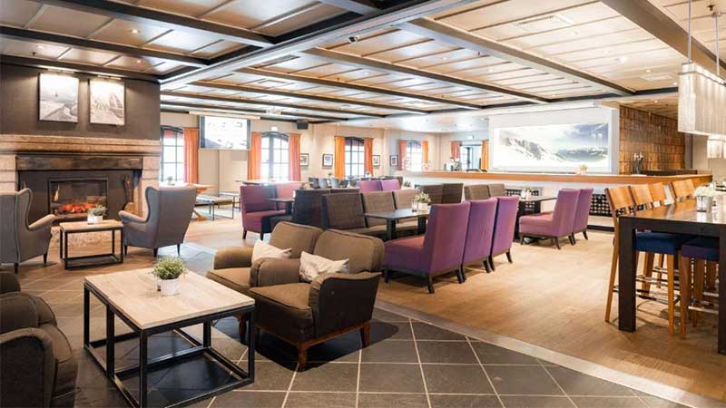 Den sk�na lobbyn p� Scandic Hotell Hafjell med �ppenspis, sk�na f�t�ljer och vacker utsikt �ver landskapet 