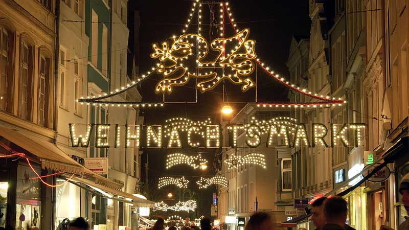 Julljus och dekorationer p� Rostocks traditionella julmarknad under en bussresa med Tj�rnarpsbuss, med gnistrande ljusslingor och festlig st�mning i Tyskland