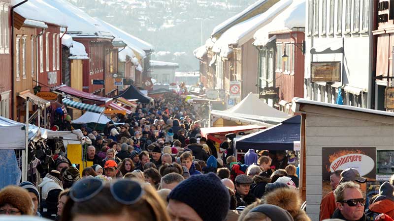 Röros marknad Livligt marknadsliv under Röros vintermarknad där delikatesser och handgjorda produkter säljs i marknadsstånden omgivna av historiska byggnader.