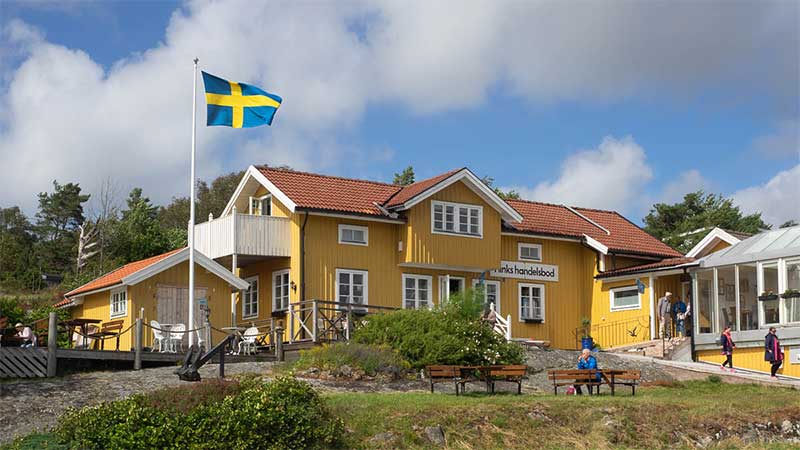 Handelsman Flinks handelsbod och restaurang p� Flat�n i Orust, Bohusl�n � gul tr�byggnad i klassisk sk�rg�rdsmilj�