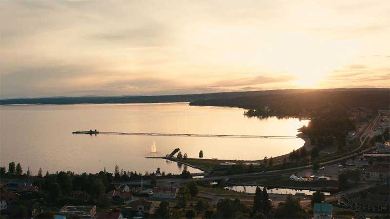 Solnedg�ng �ver Siljan med vy mot R�ttvik, spegelblank sj� och siluett av tr�brygga och skog
