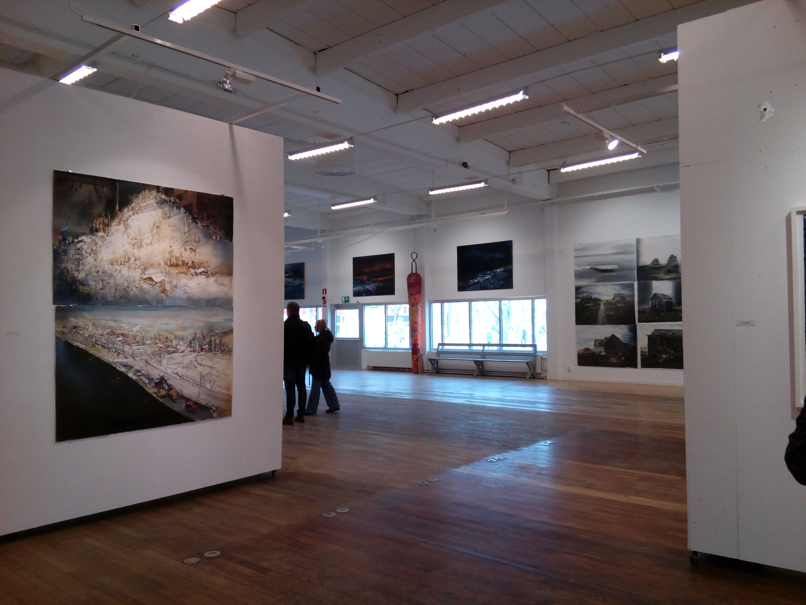 Interi�r fr�n Lars Lerins konsthall Sandgrund i Karlstad med stora akvarellm�lningar p� vita v�ggar. Ljust galleri med tr�golv, h�gt tak och bes�kare som betraktar konstverken.