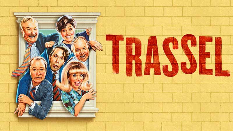 Skadespelare i Trassel poserar framför gul tegelfasad scen från fartfylld teater med humor och karaktär i Stockholm